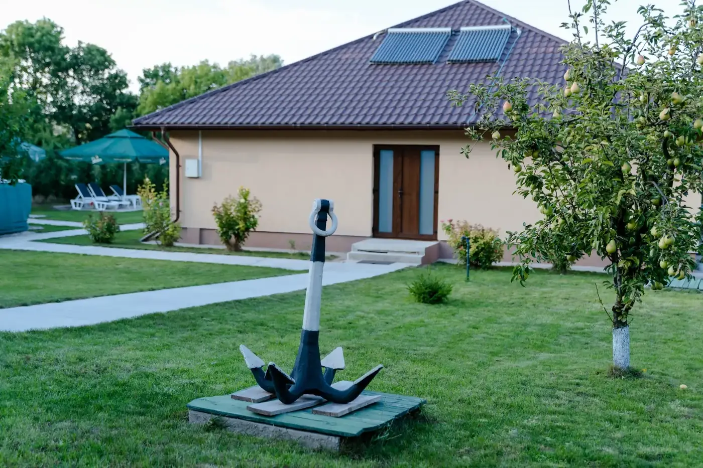 Curtea Pensiunii Dunărea, cu grădină și ancora decorativă